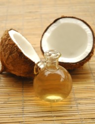 A bottle of coconut oil with two coconut halves.
